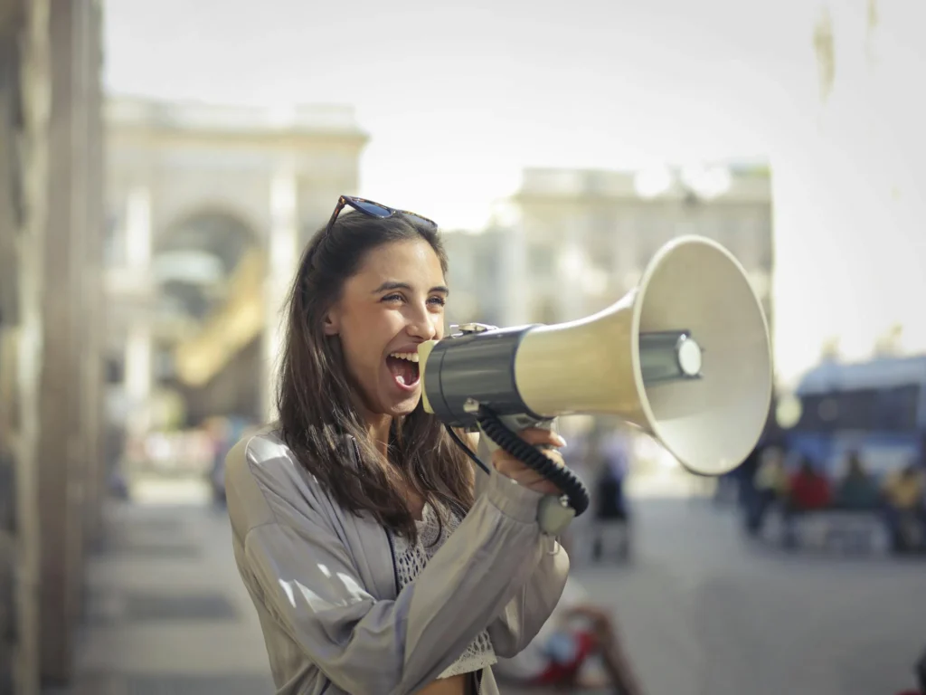 In the image a girl holding a megaphone